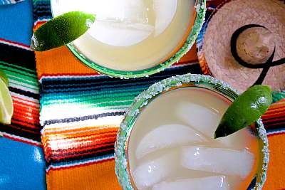 Three glasses of mexican margaritas on a colorful tablecloth.