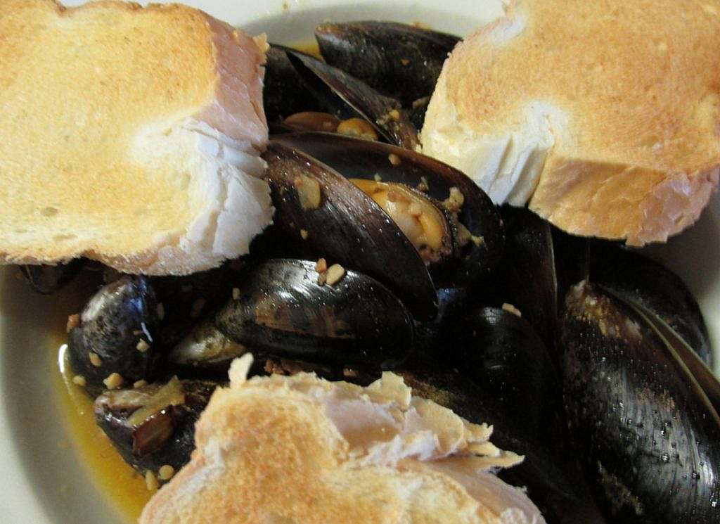 Mussels and bread in a white bowl.