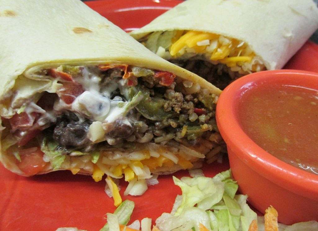 Two burritos on a red plate with dipping sauce.